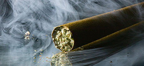 Marijuana blunt on a table surrounded by smoke