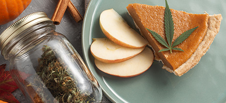 Mason jar with cannabis flower inside, next to a plate with a slice of pumpkin pie with a cannabis leaf on top