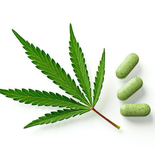 THC pills in front of a cannabis leaf