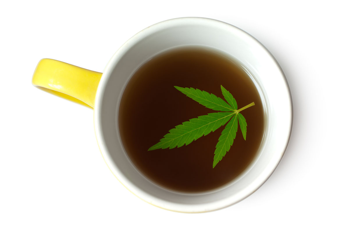 Looking down at a fan leaf floating in a mug of cannabis tea