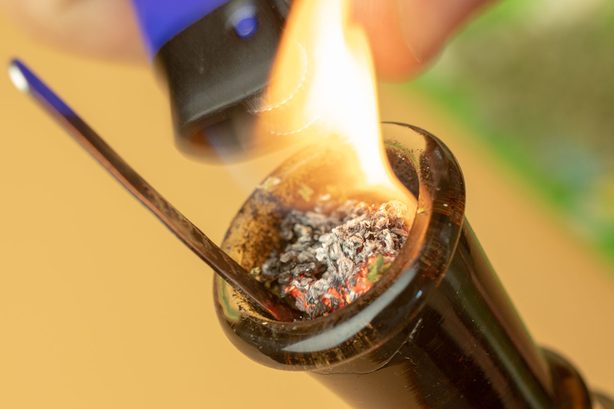Cannabis flower in the bowl of a bong being lit by a lighter