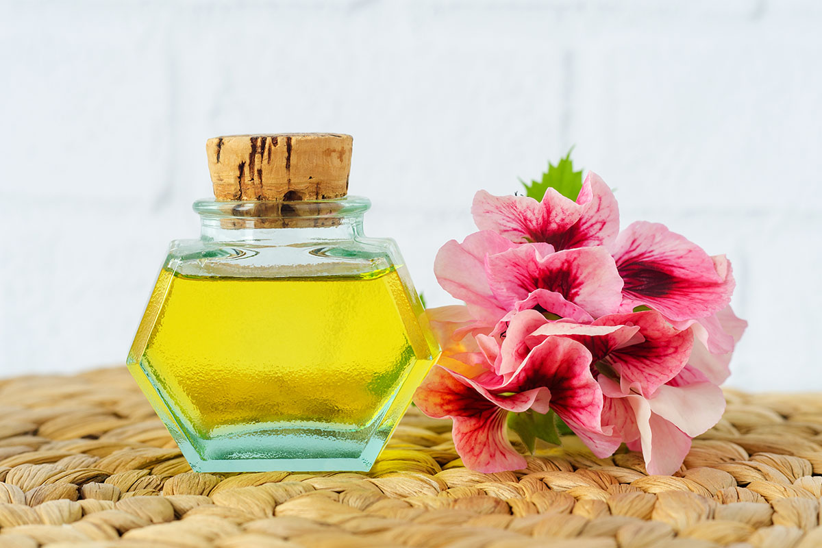 Essential oil bottle next to a bunch of geraniums