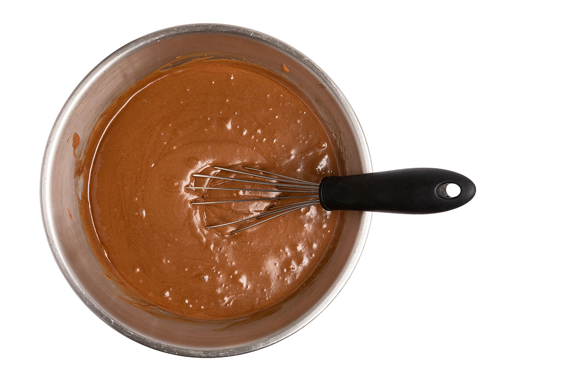 Brownie batter in a mixing bowl with a whisk sitting in it
