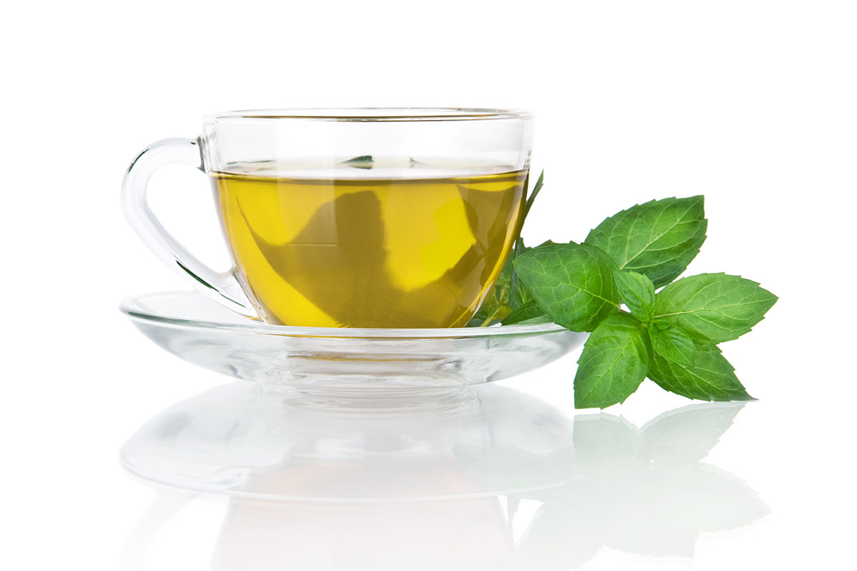 Cup of peppermint tea with a peppermint leaf next to it