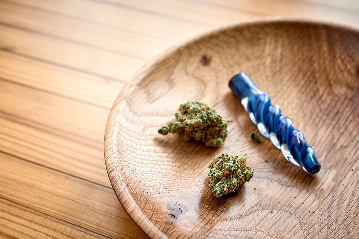 One hitter on a wooden tray next to two flower buds