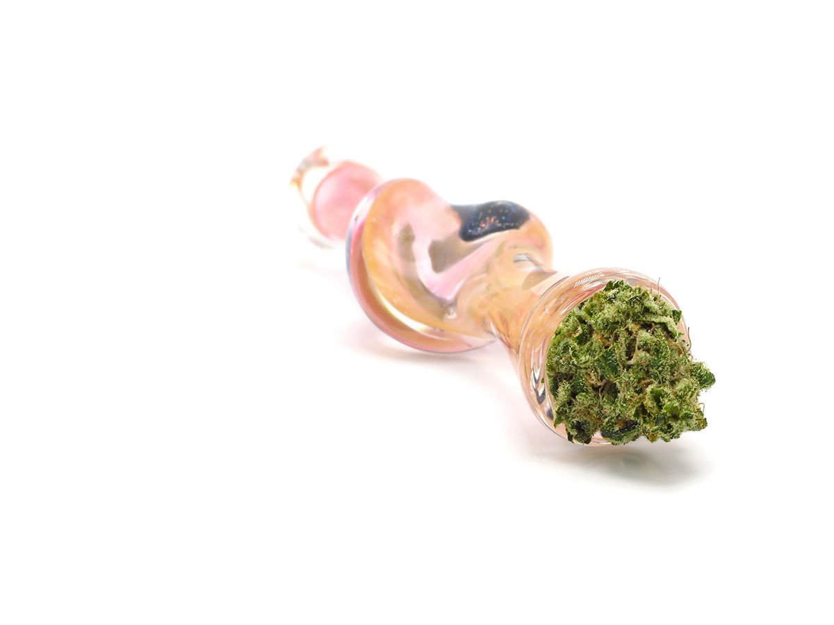 Pink one-hitter with cannabis flower sticking out of the bowl