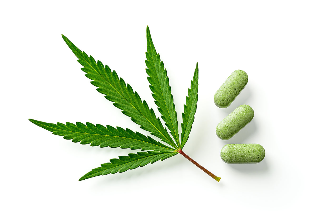 Cannabis leaf next to three green pills