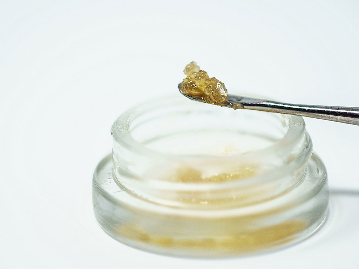 Terp sauce being scooped out of a clear container with a dab tool