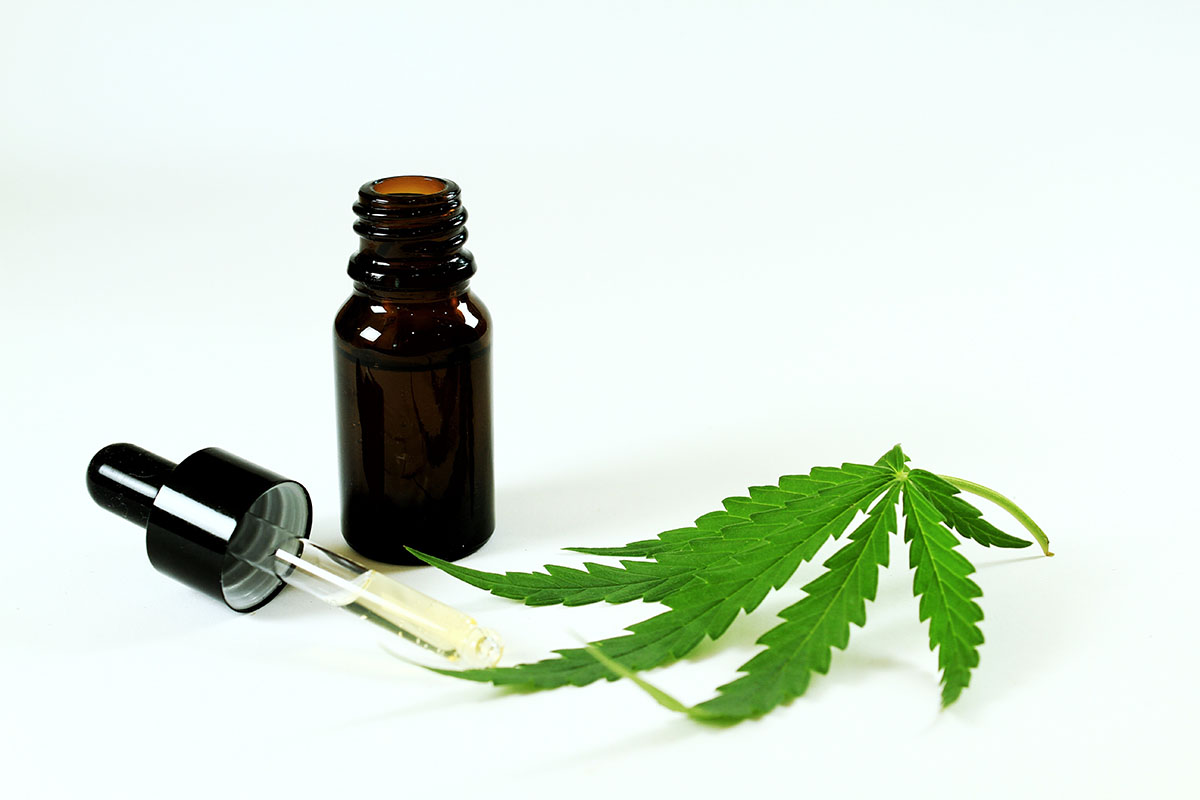 Tincture bottle next to a dropper and a cannabis leaf